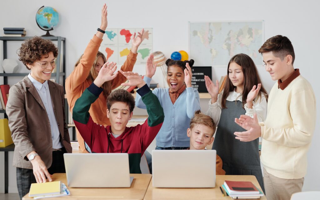 Students standing around computers cheering